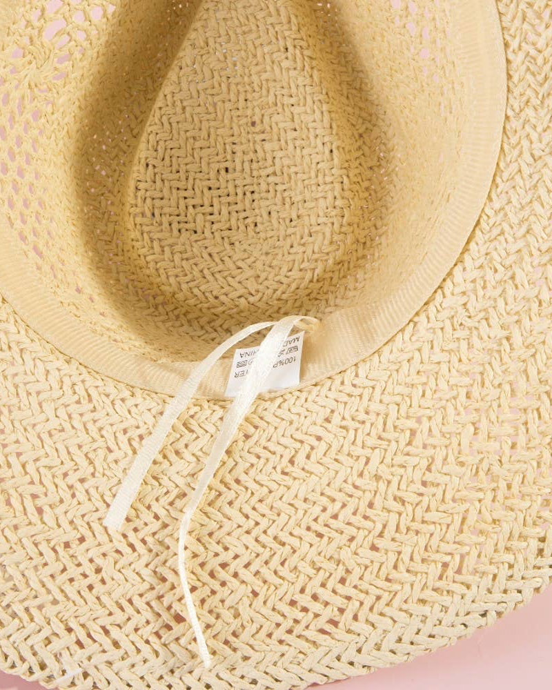 Close-up of a straw hat with a tag on a pink background