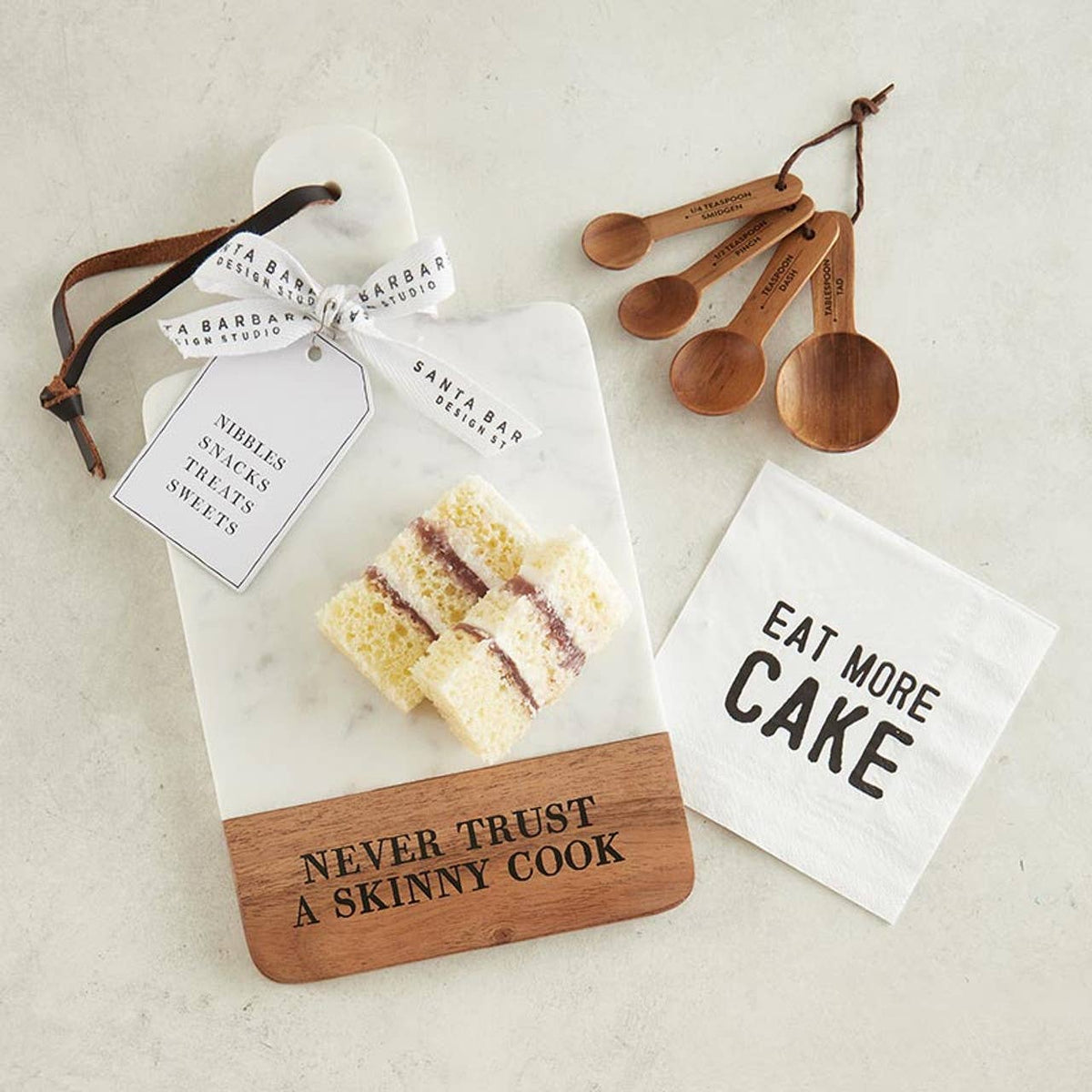 Set of kitchen items including a cutting board, measuring spoons, and a napkin with text on a light background