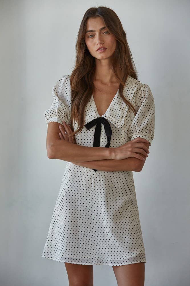 Swiss dot chiffon mini dress with collared V-neck, short sleeves, front velvet bow, and A-line silhouette with back zipper and button keyhole.