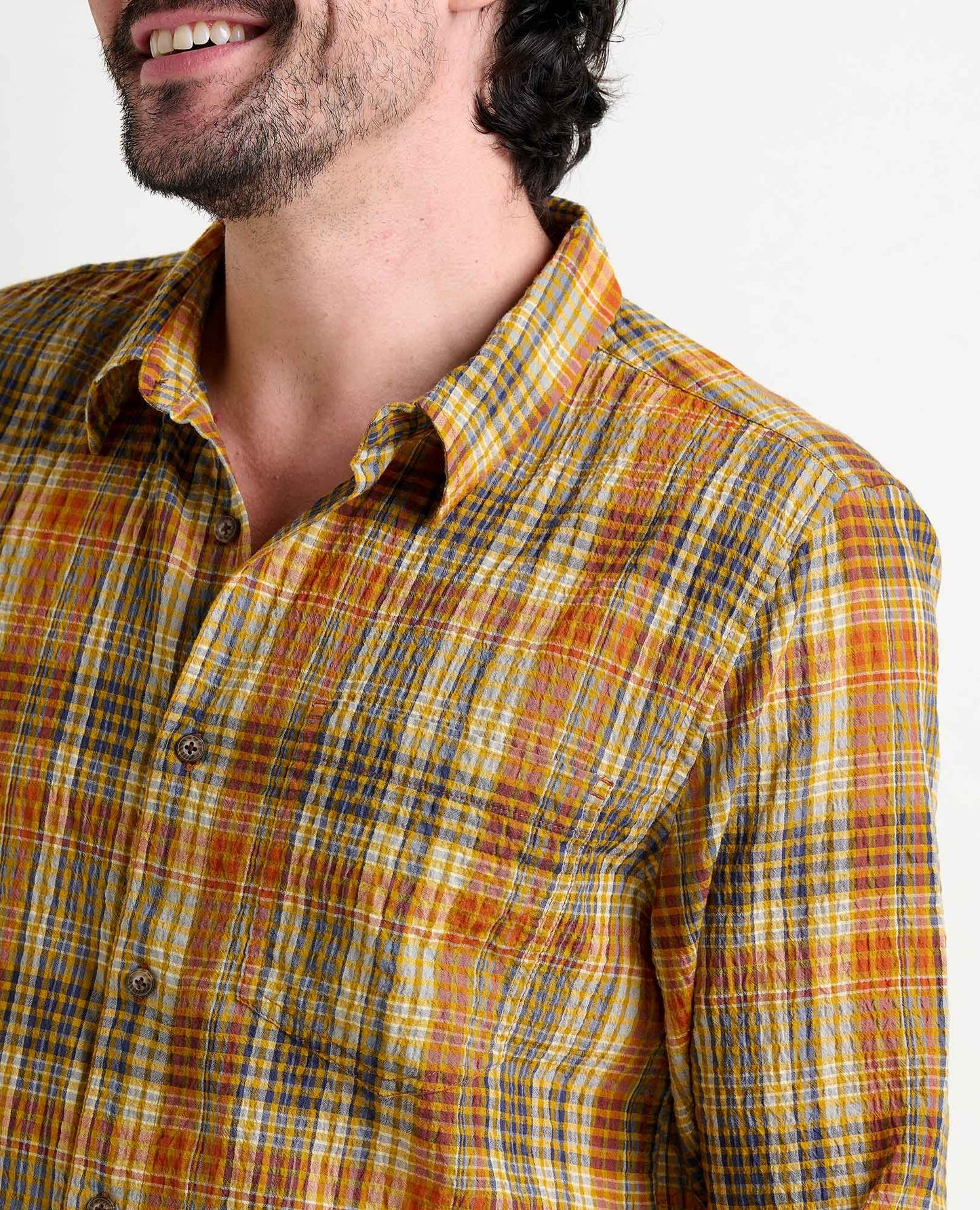 Man wearing a yellow and blue plaid shirt on a white background