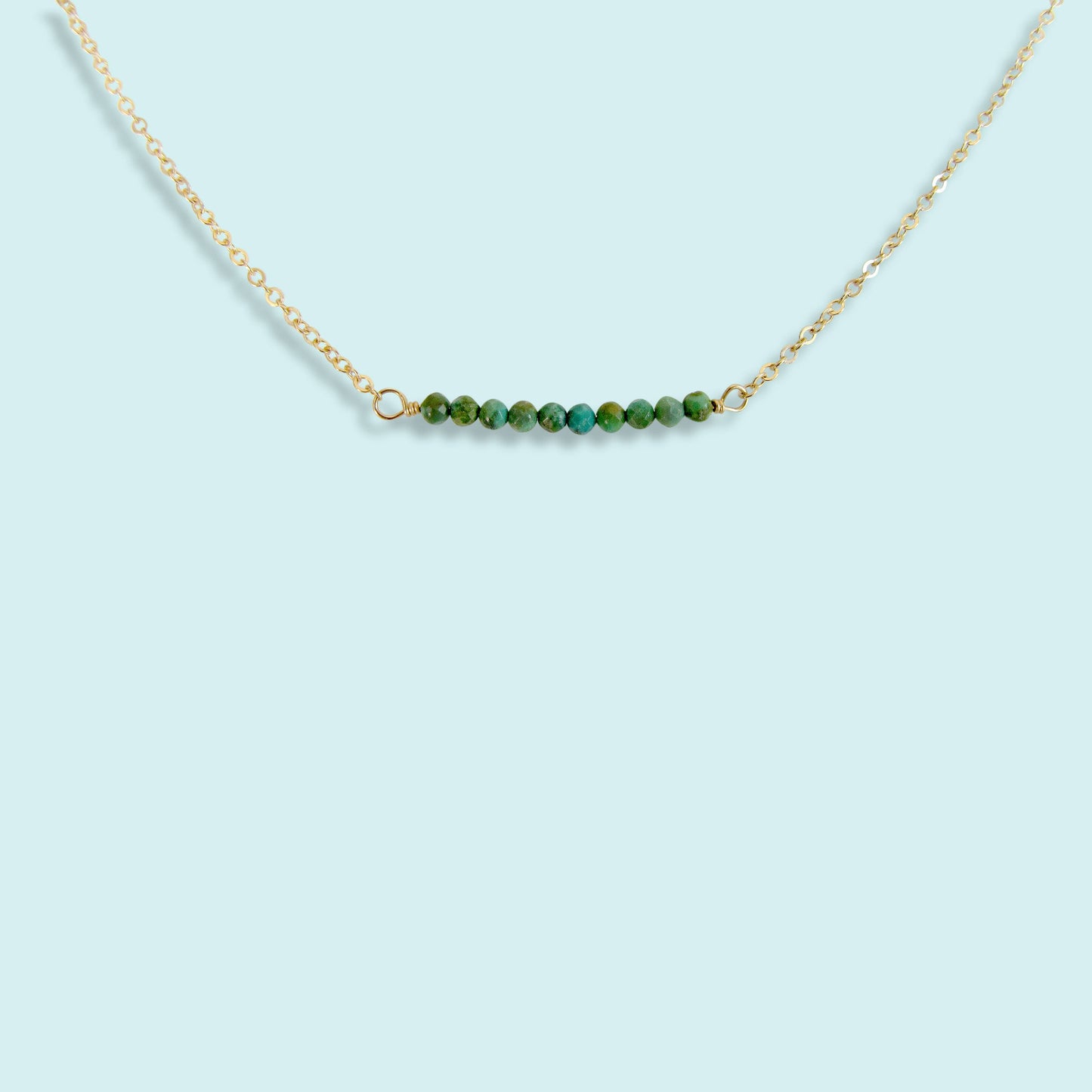 Necklace with green beads on a light blue background