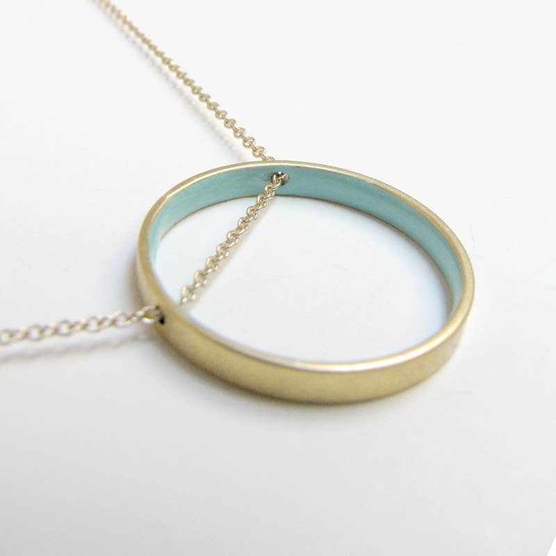 Gold necklace with a round pendant on a white background