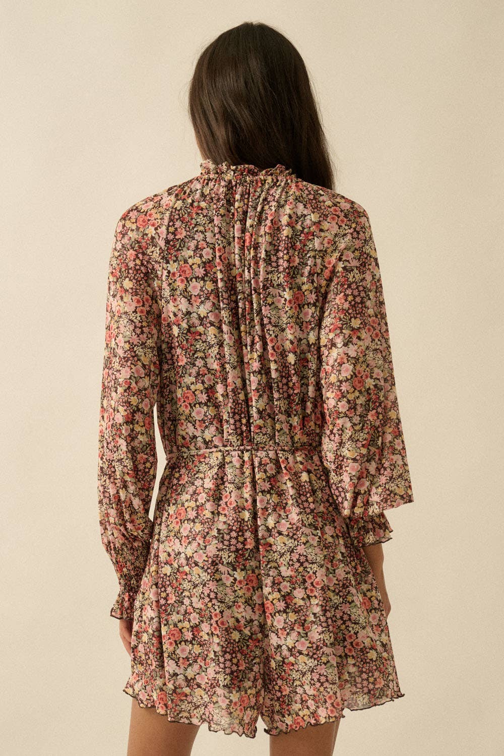 Woman wearing a floral dress with long sleeves on a beige background