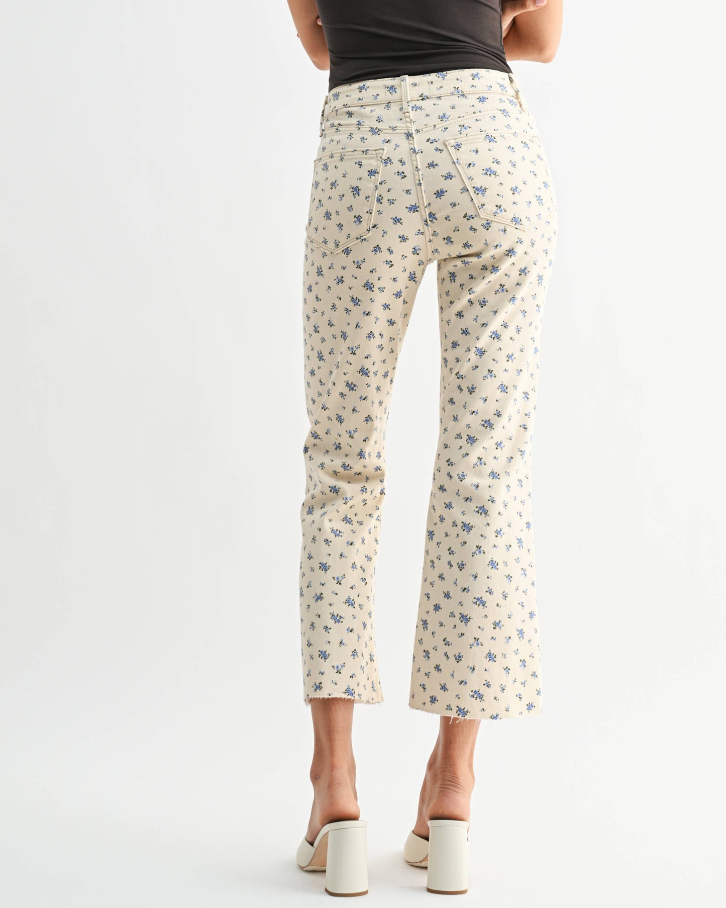 Woman wearing a black top and white floral pants on a white background