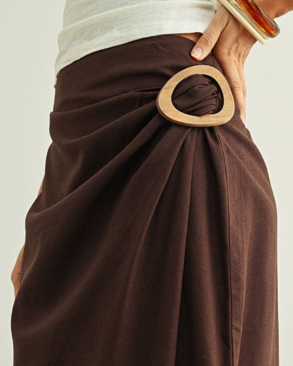 Brown wrap skirt with wooden belt on a plain background