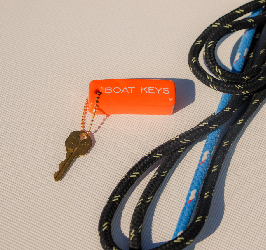 Key with an orange 'BOAT KEYS' tag attached to a black and blue rope on a textured surface.
