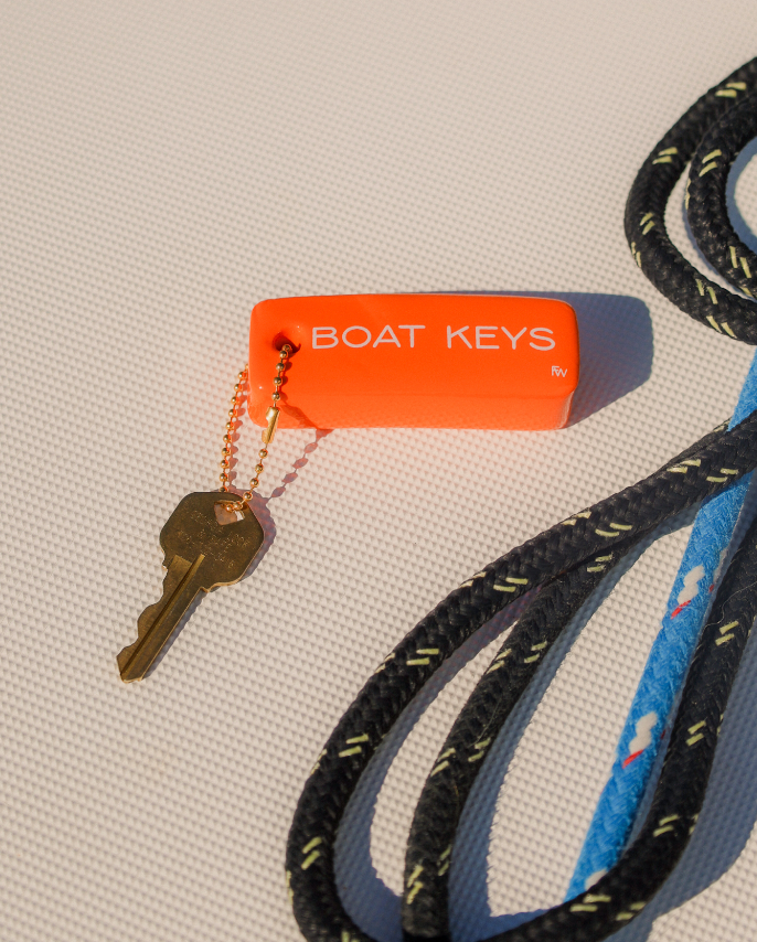 Key with an orange 'BOAT KEYS' tag attached to a black and blue rope on a textured surface.