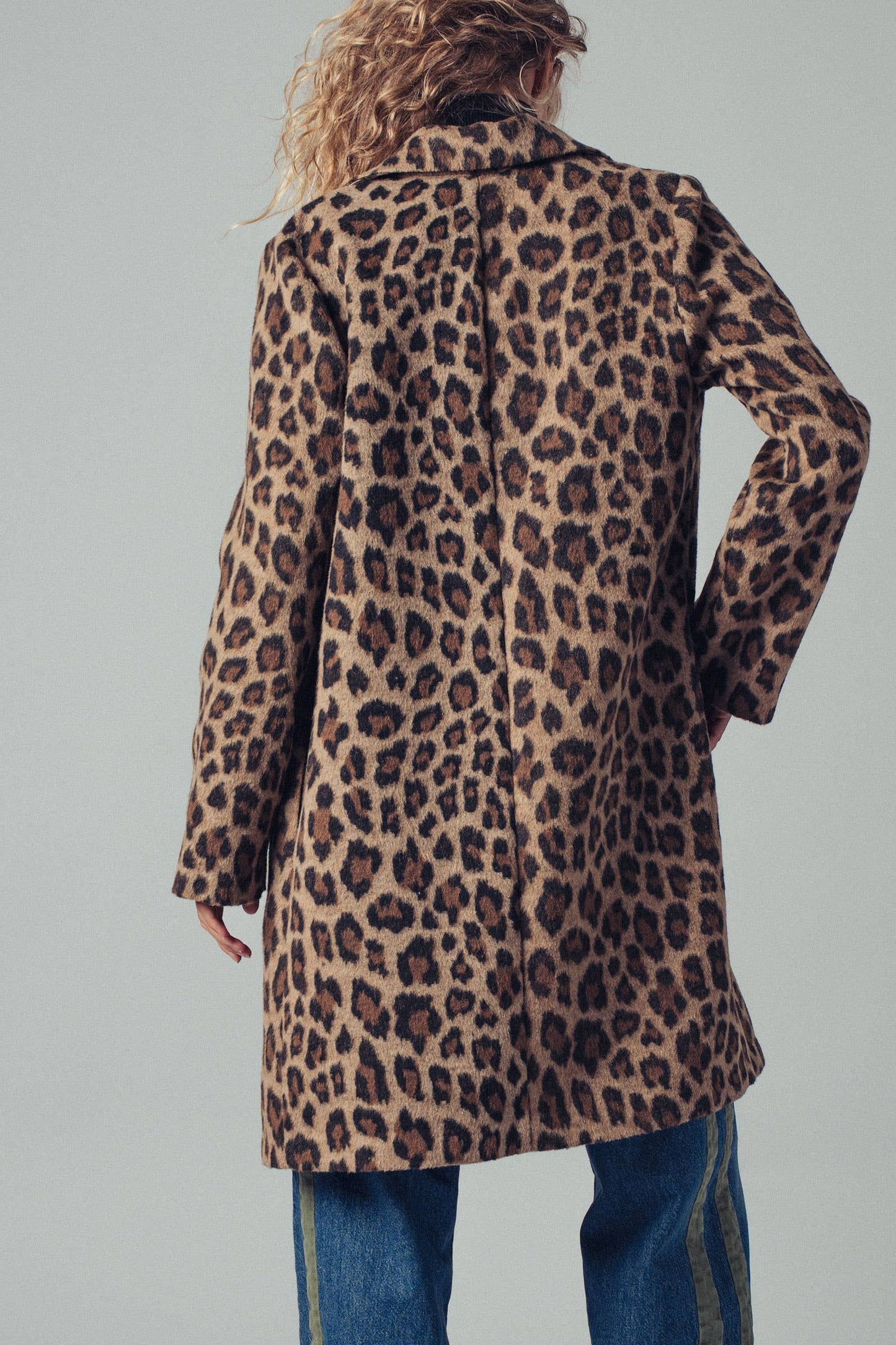 Person wearing a leopard print coat on a plain background