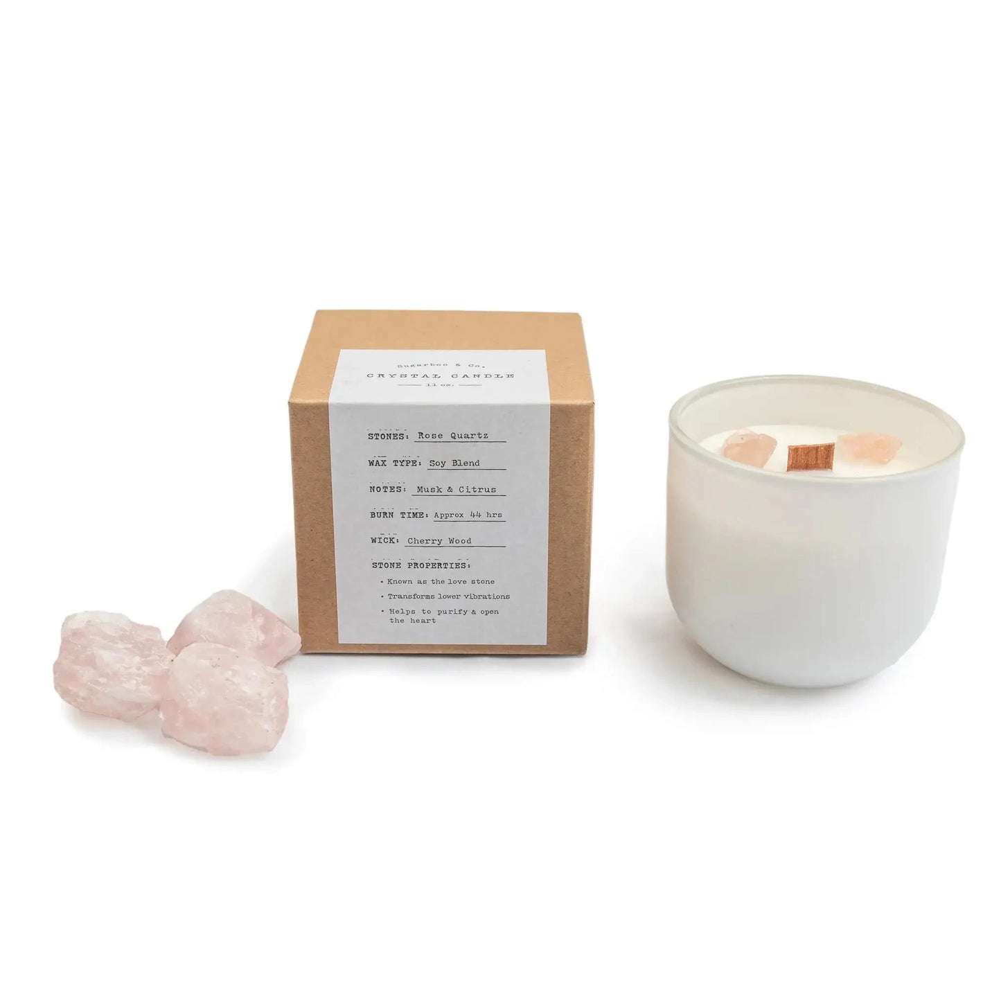 White candle in a ceramic holder with a cardboard box and pink crystal on a white background