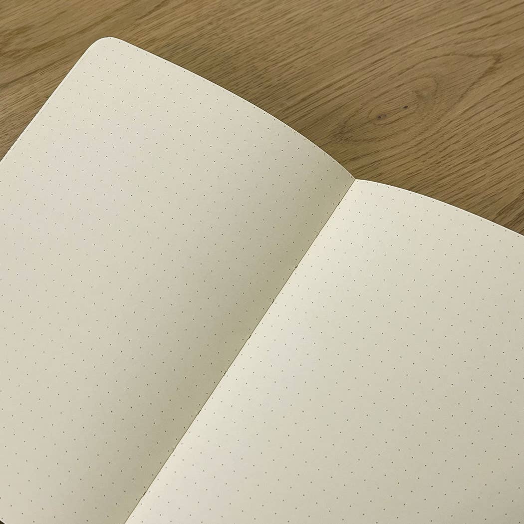 Open notebook with dot grid pages on a wooden surface