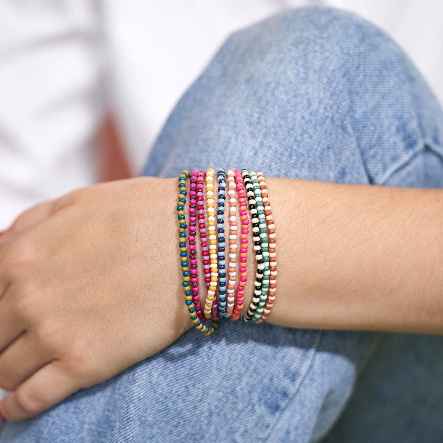 Multicolored beaded bracelets on a wrist with a blurred background