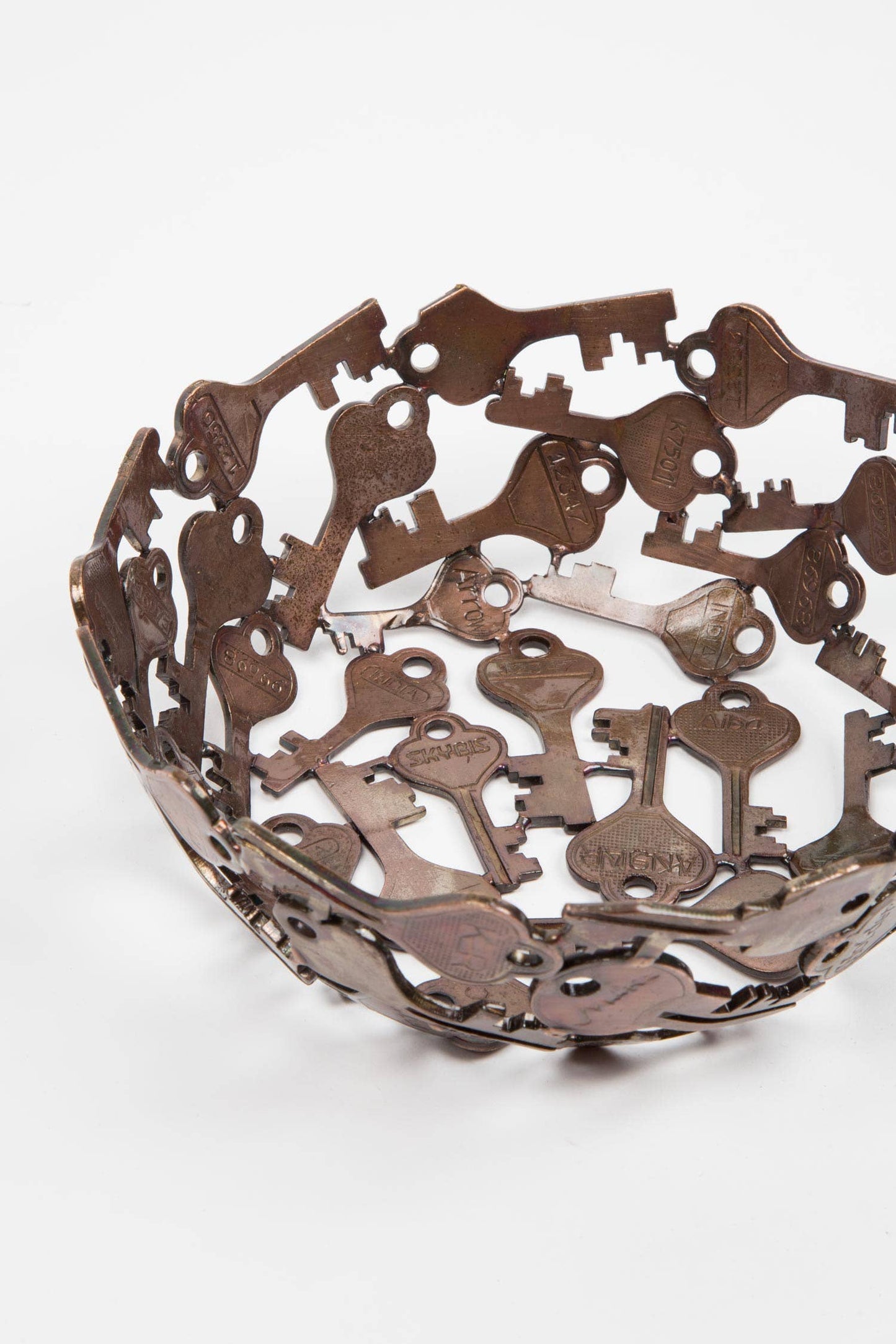 Decorative bowl made from cut-out metal keys on a white background