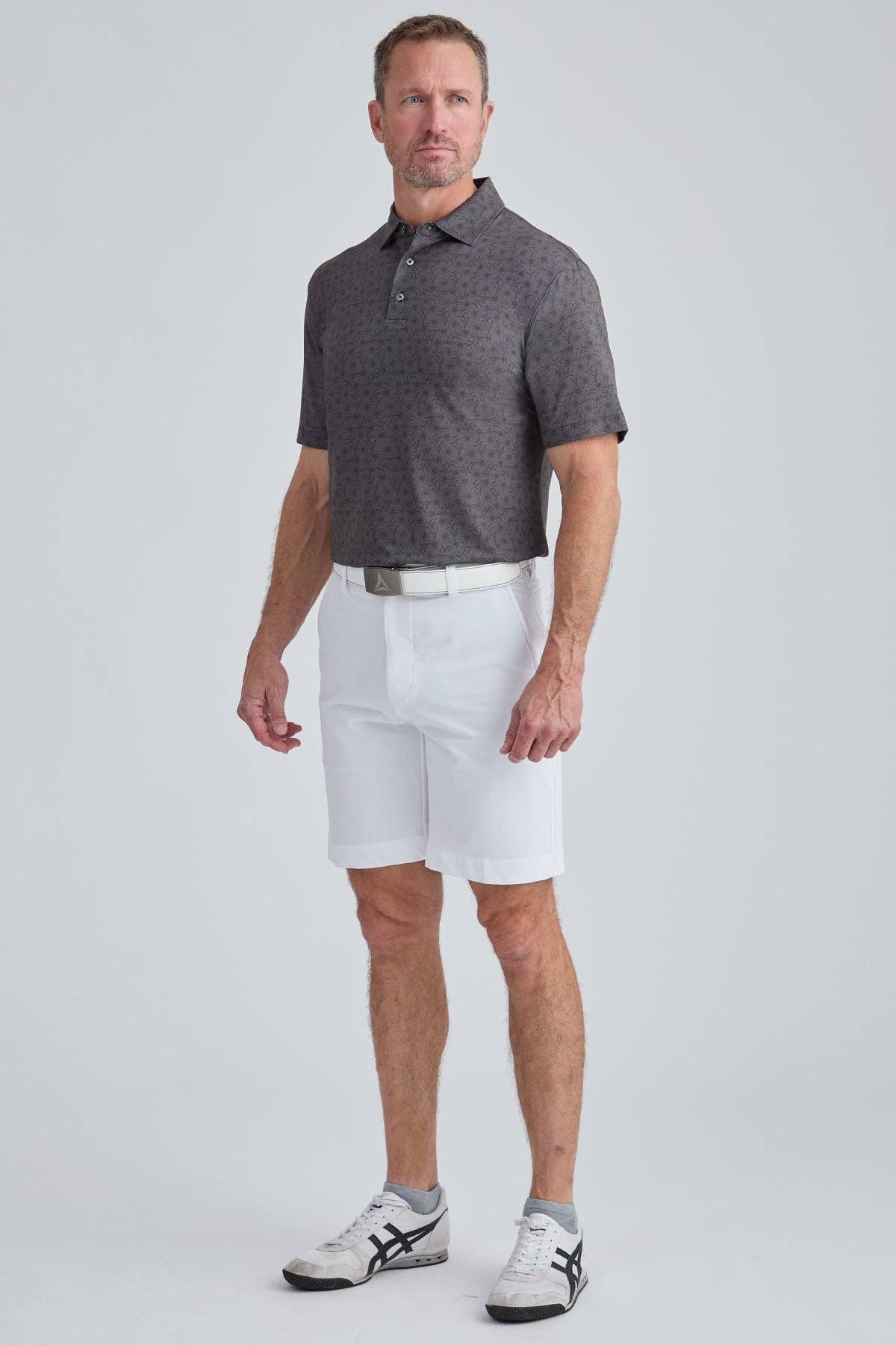 Man wearing a gray polo shirt and white shorts on a light gray background