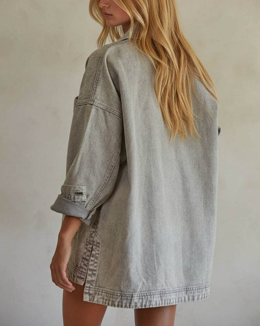 Woman wearing a light gray denim jacket against a plain background