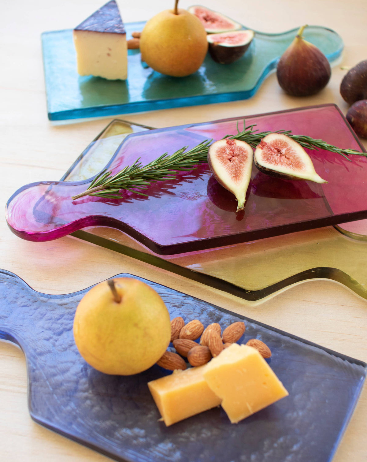 Assorted fruits and cheeses on colorful glass cutting boards.