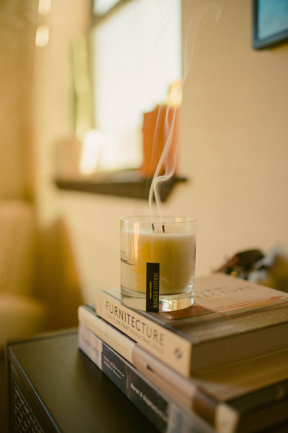 Candle in a glass holder on top of books with a blurred background