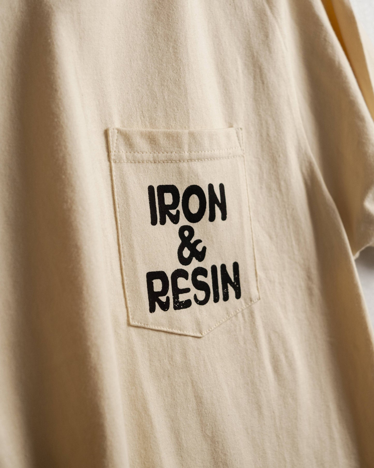 Beige shirt with 'IRON & RESIN' logo on a pocket