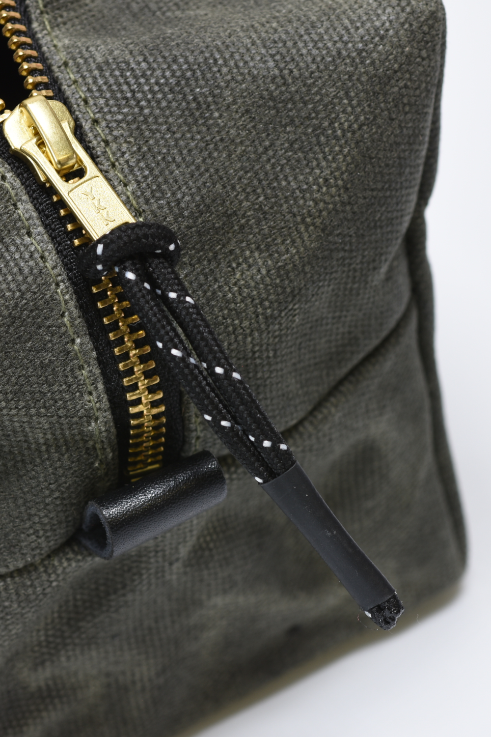 Green fabric bag with gold zipper and black拉链 on a white background