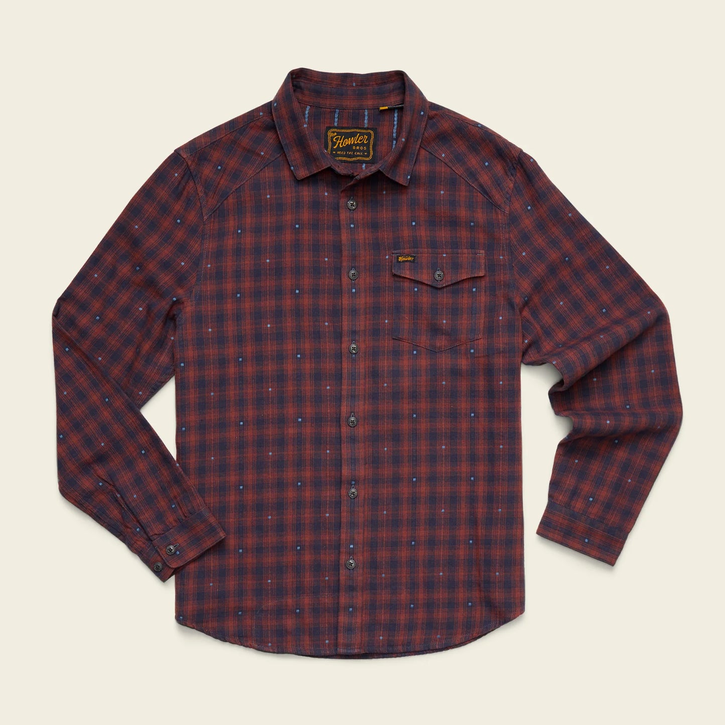A long-sleeve button-up shirt by Barbour, featuring a red and navy blue plaid pattern with a subtle dotted texture, laid flat against a light cream background.