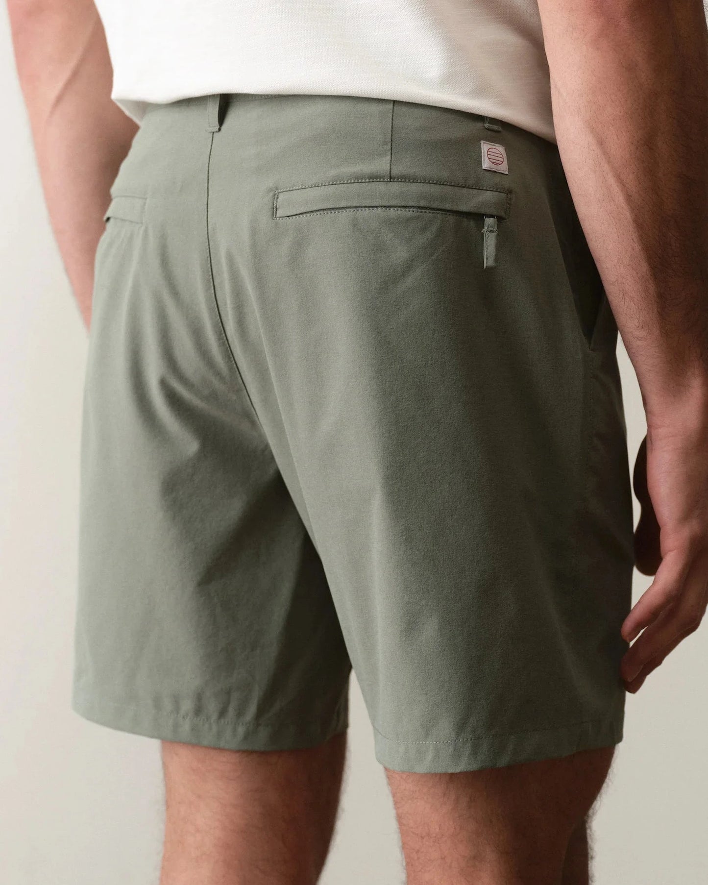 Person wearing green shorts and a white shirt against a neutral background