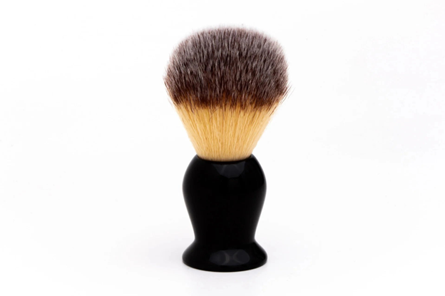 Shaving brush with black handle and brown bristles on a white background