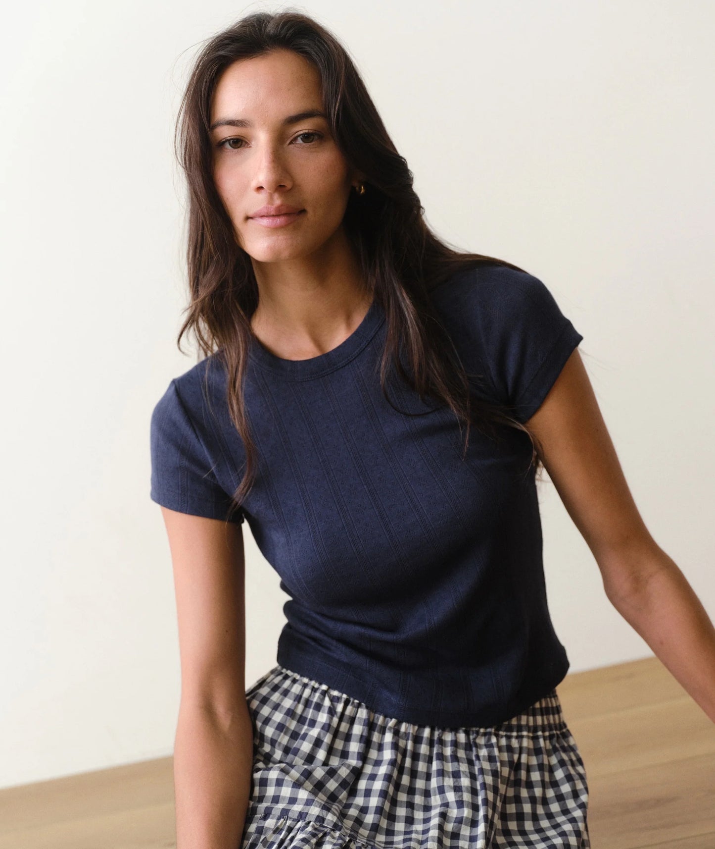 Woman wearing a navy blue t-shirt and checkered pants against a plain background
