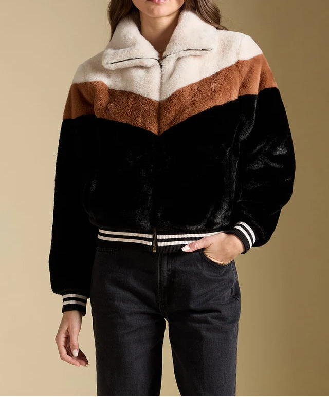 Woman wearing a black, brown, and white striped jacket against a beige background