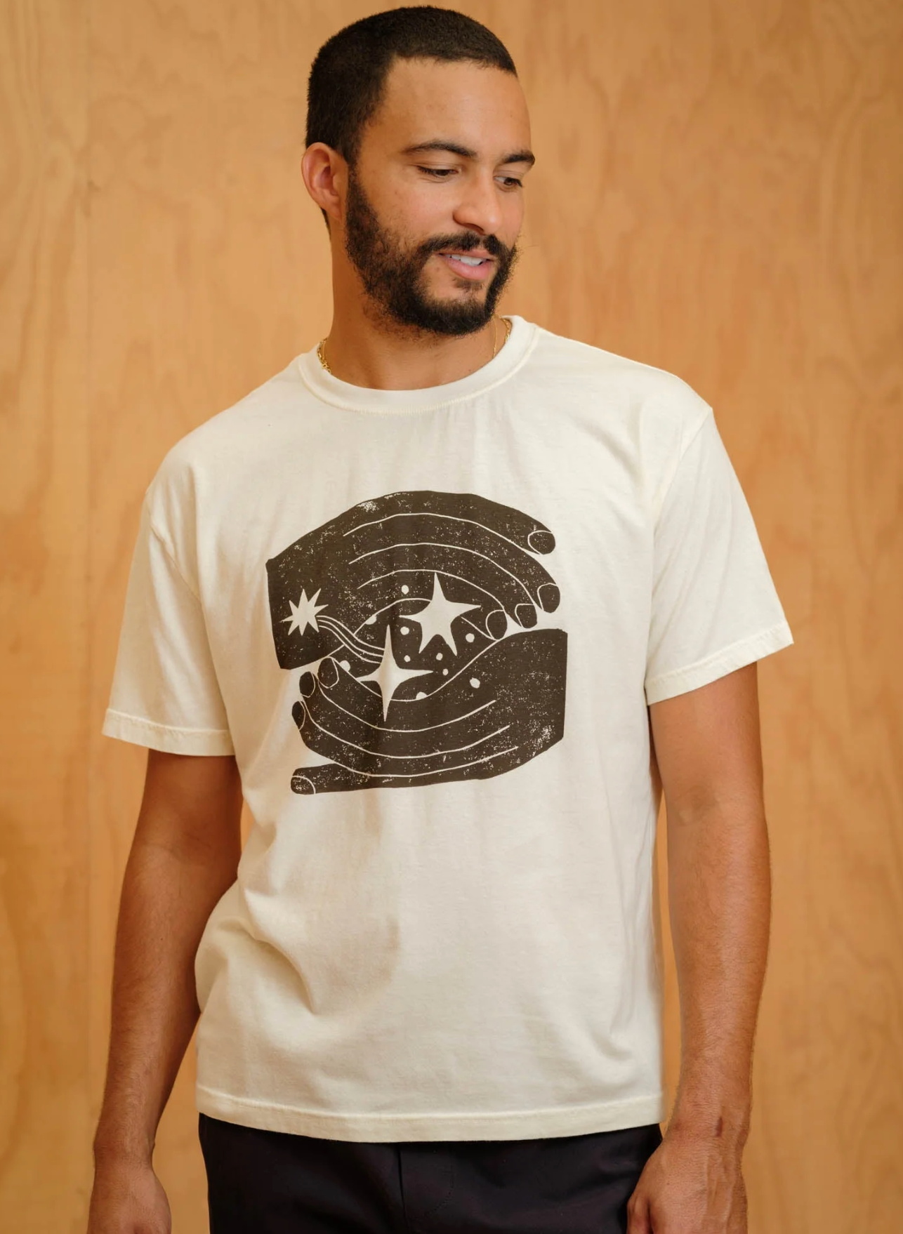 Man wearing a white t-shirt with a graphic design on a wooden background