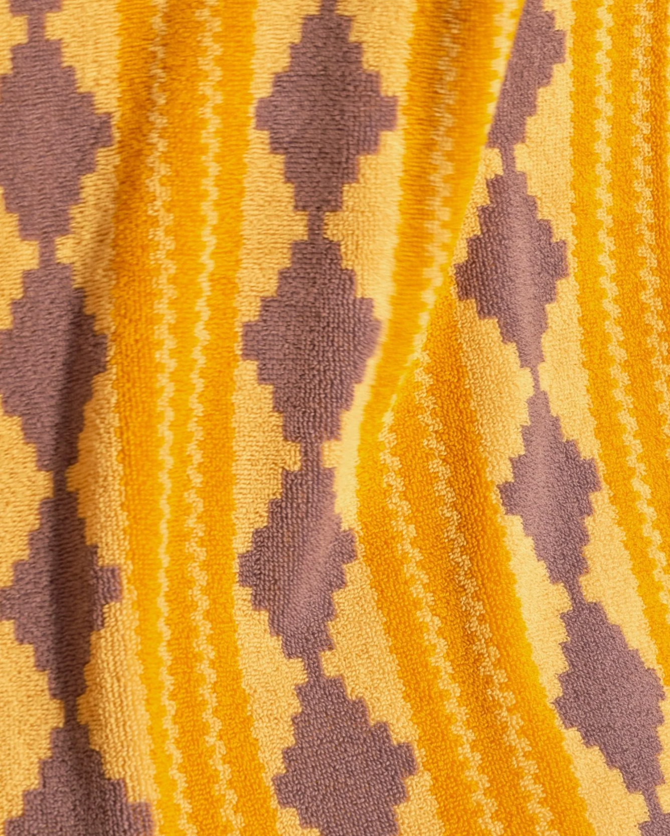 Close-up of a textured fabric with a geometric pattern in orange and purple.
