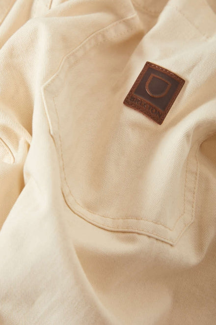 Close-up of a beige jacket with a brand logo on the chest pocket.