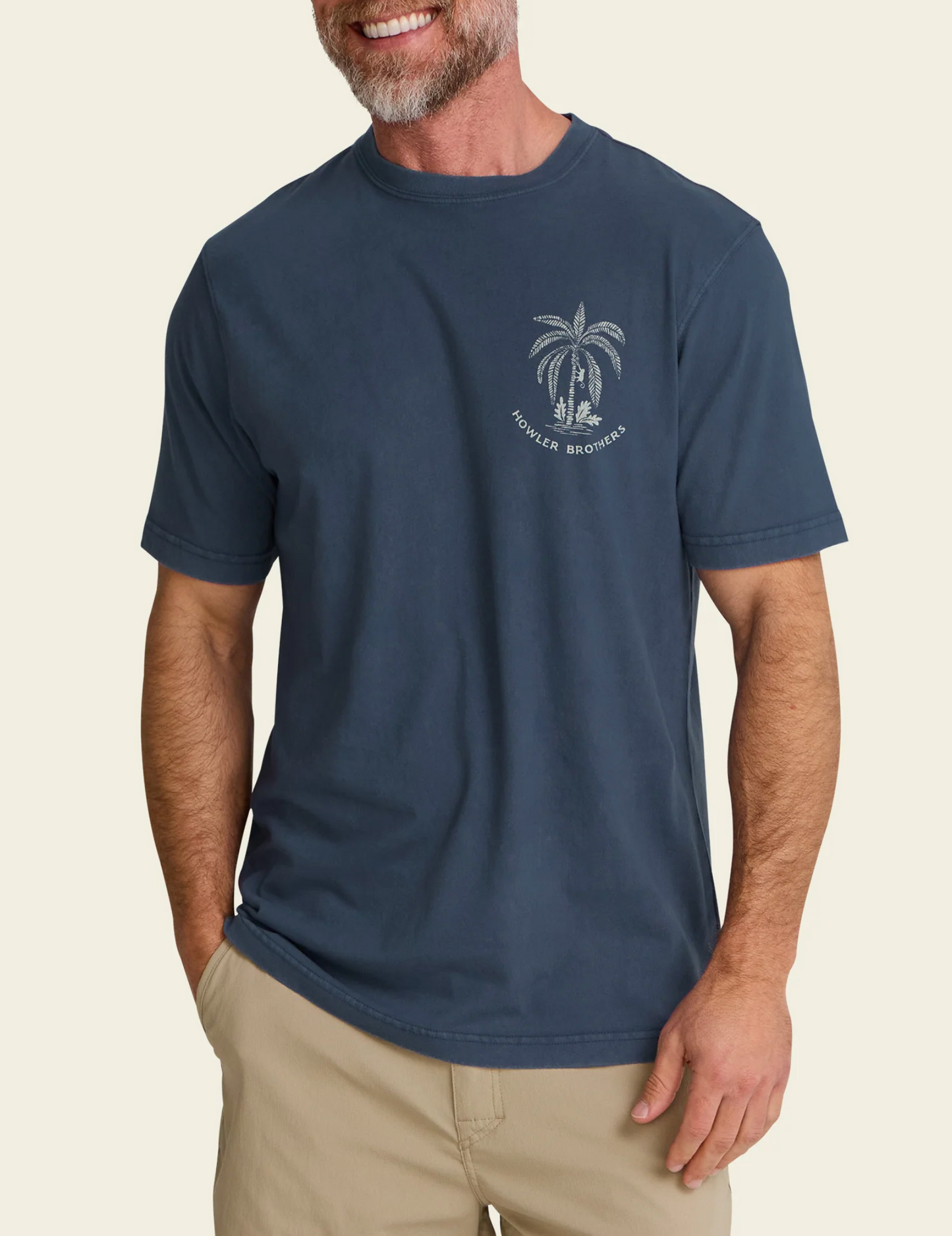 Man wearing a navy blue t-shirt with a palm tree design on a beige background