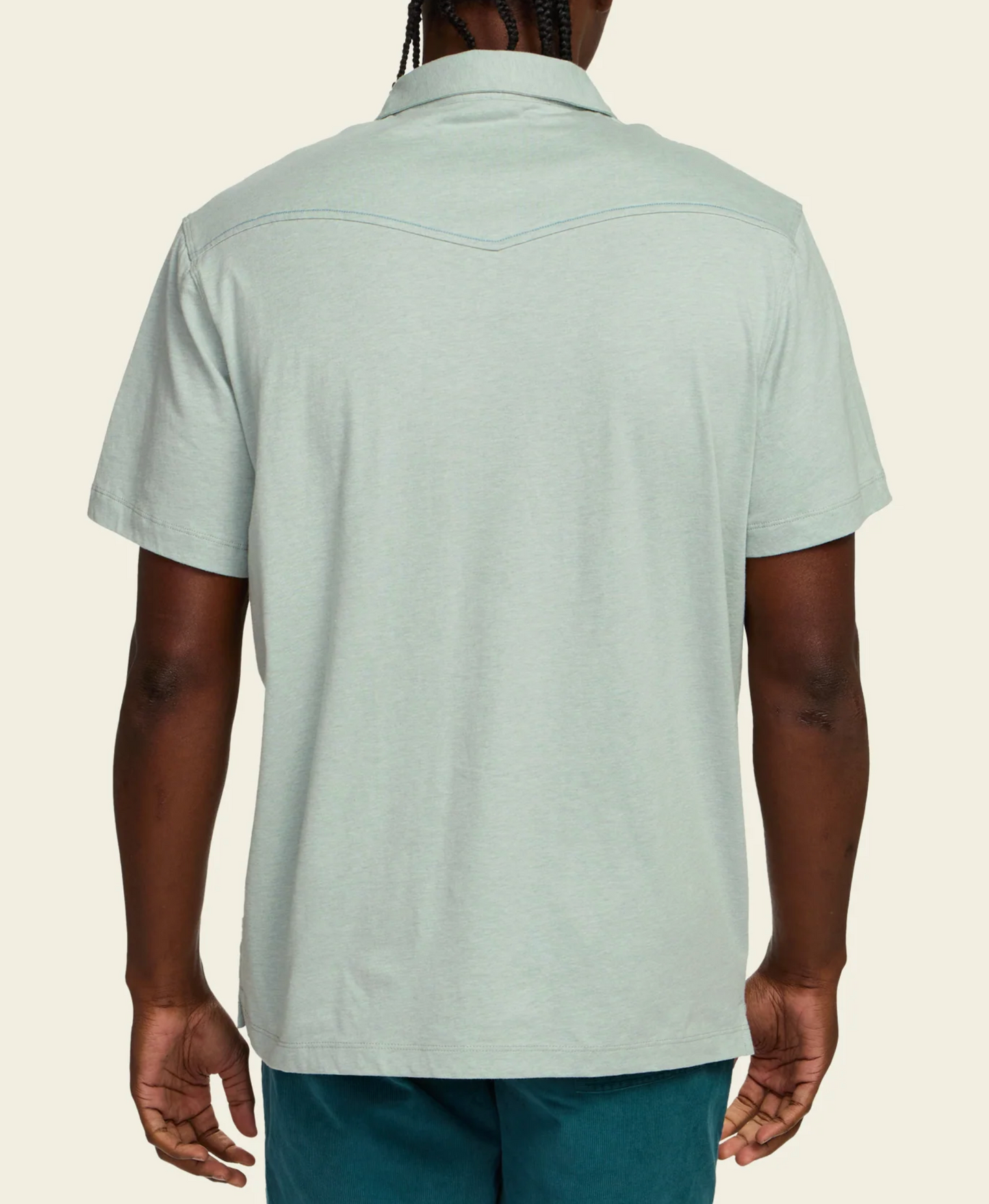 Person wearing a light green short-sleeve shirt on a beige background