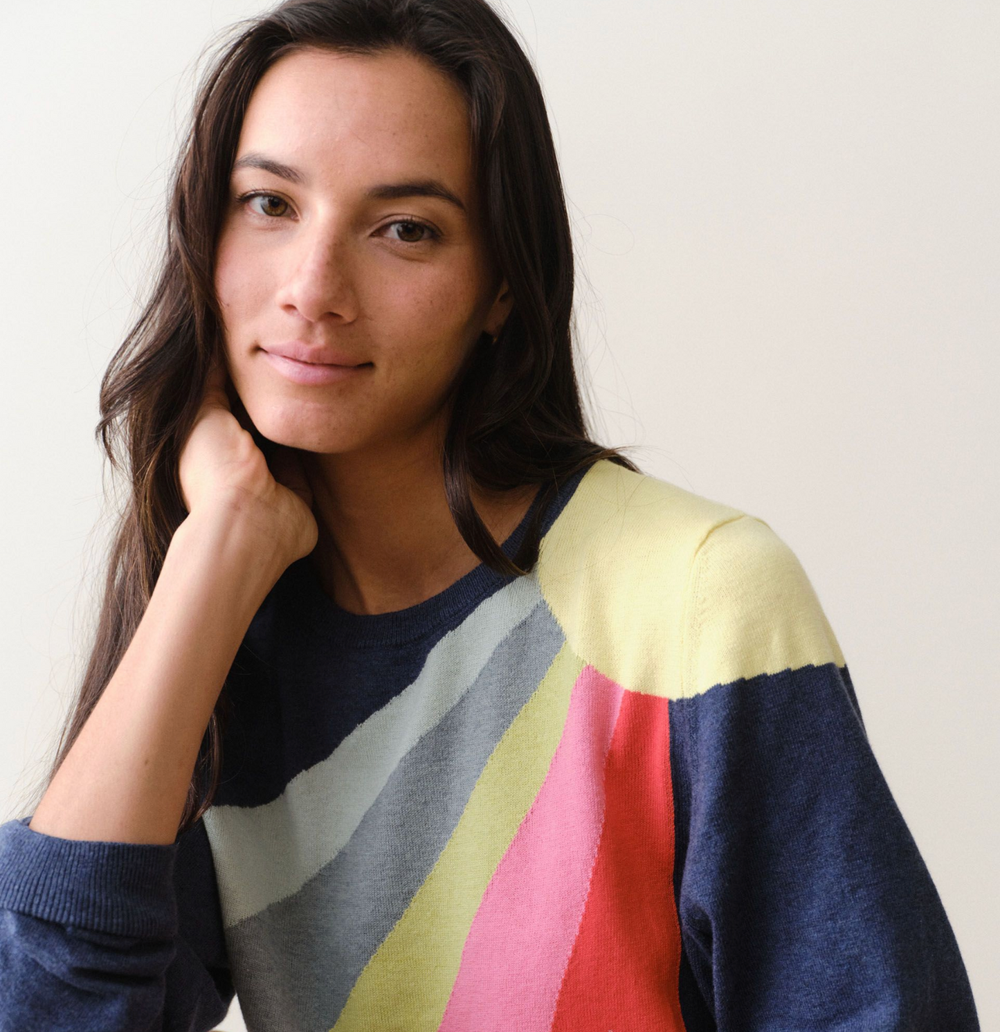 Woman wearing a colorful striped sweater against a plain background