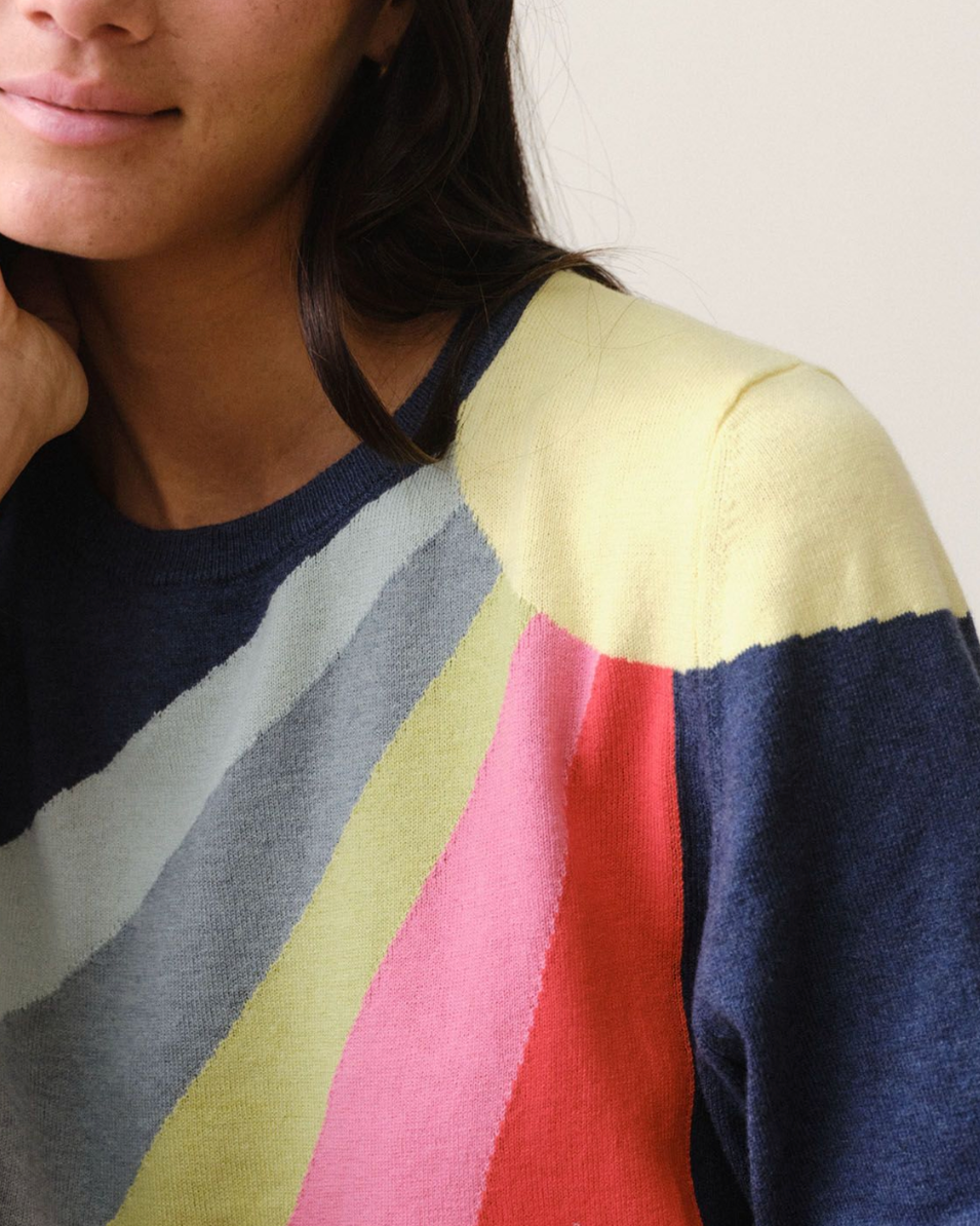 Woman wearing a colorful striped sweater against a plain background