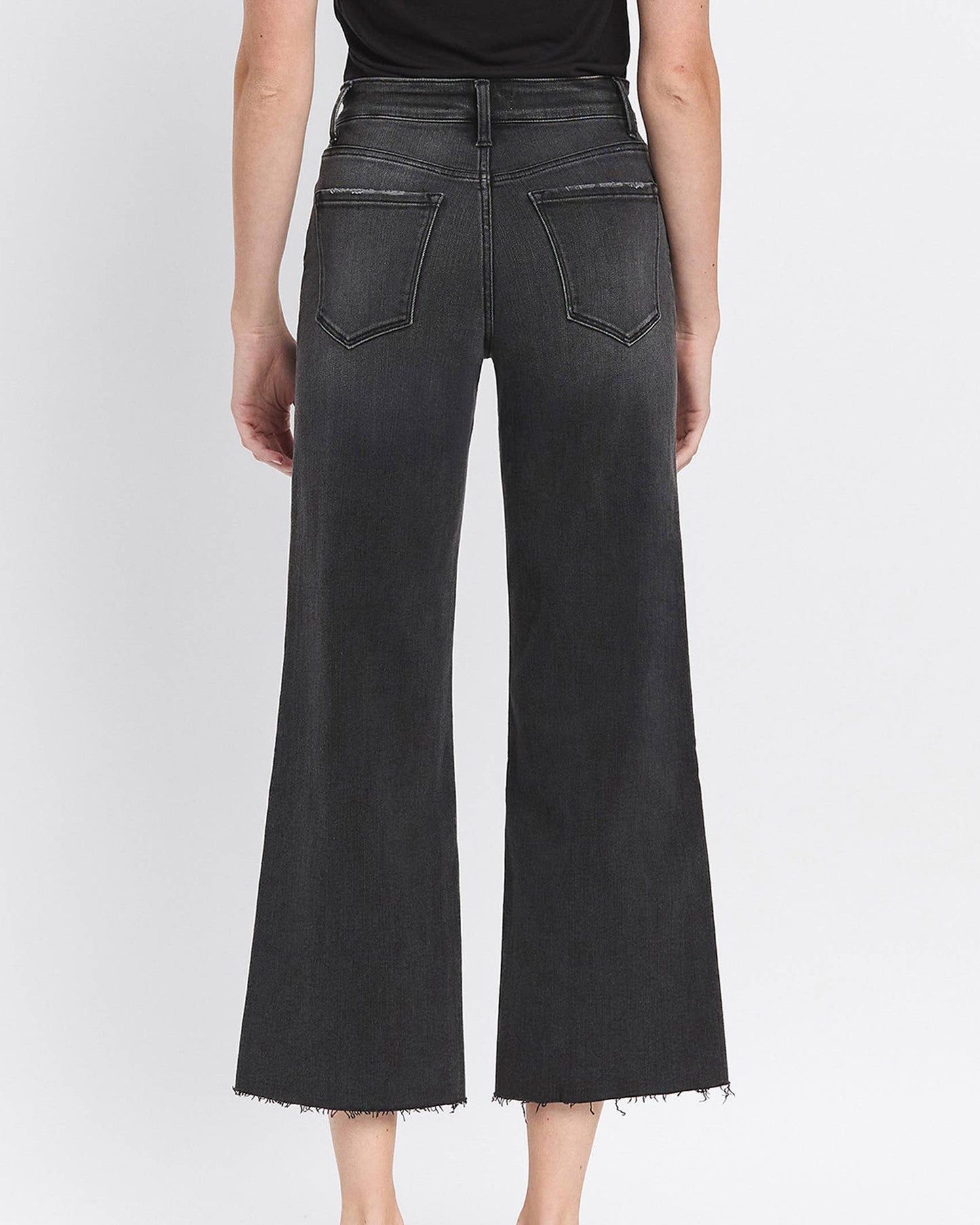 Person wearing black wide-leg jeans on a white background