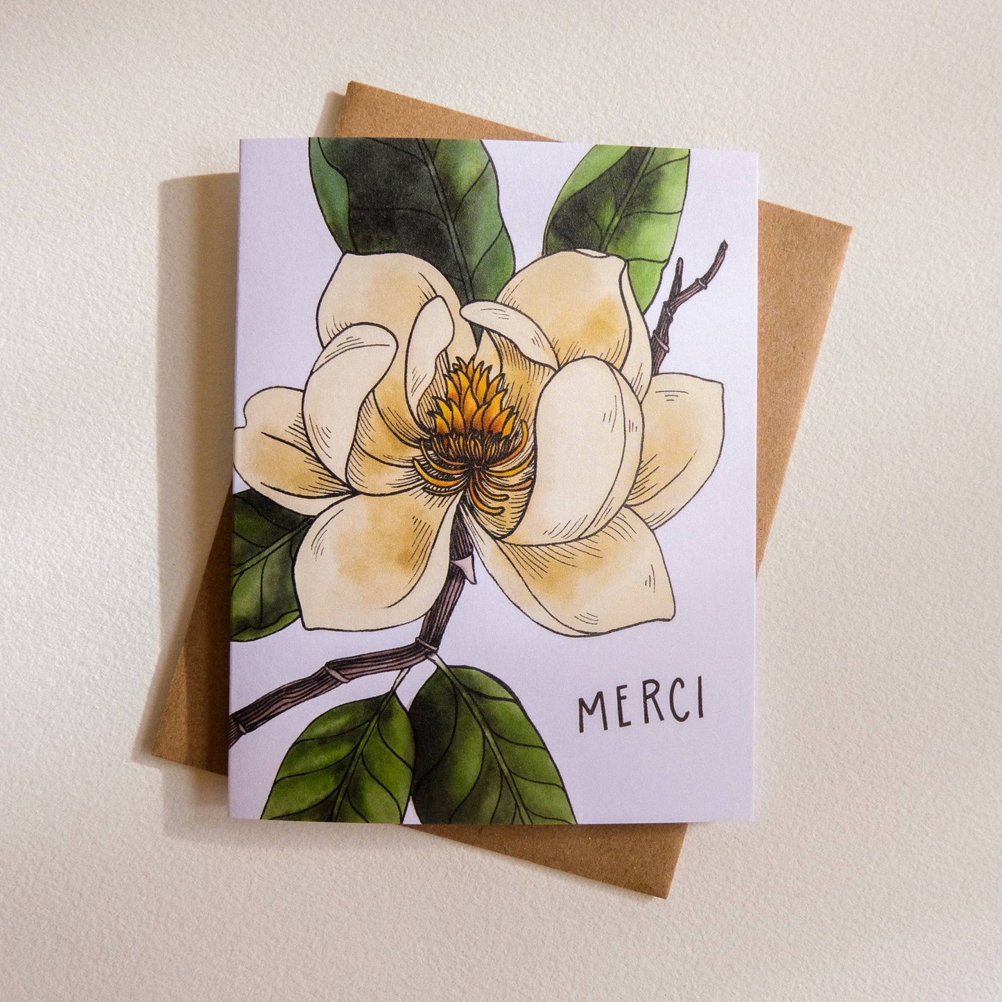 Card with floral design and 'MERCI' text on a beige background