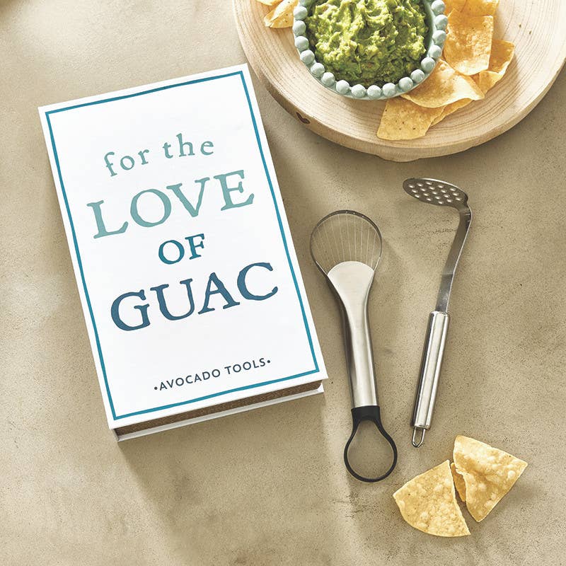 Avocado tools with a book titled 'For the Love of Guac' on a table with guacamole and tortilla chips.