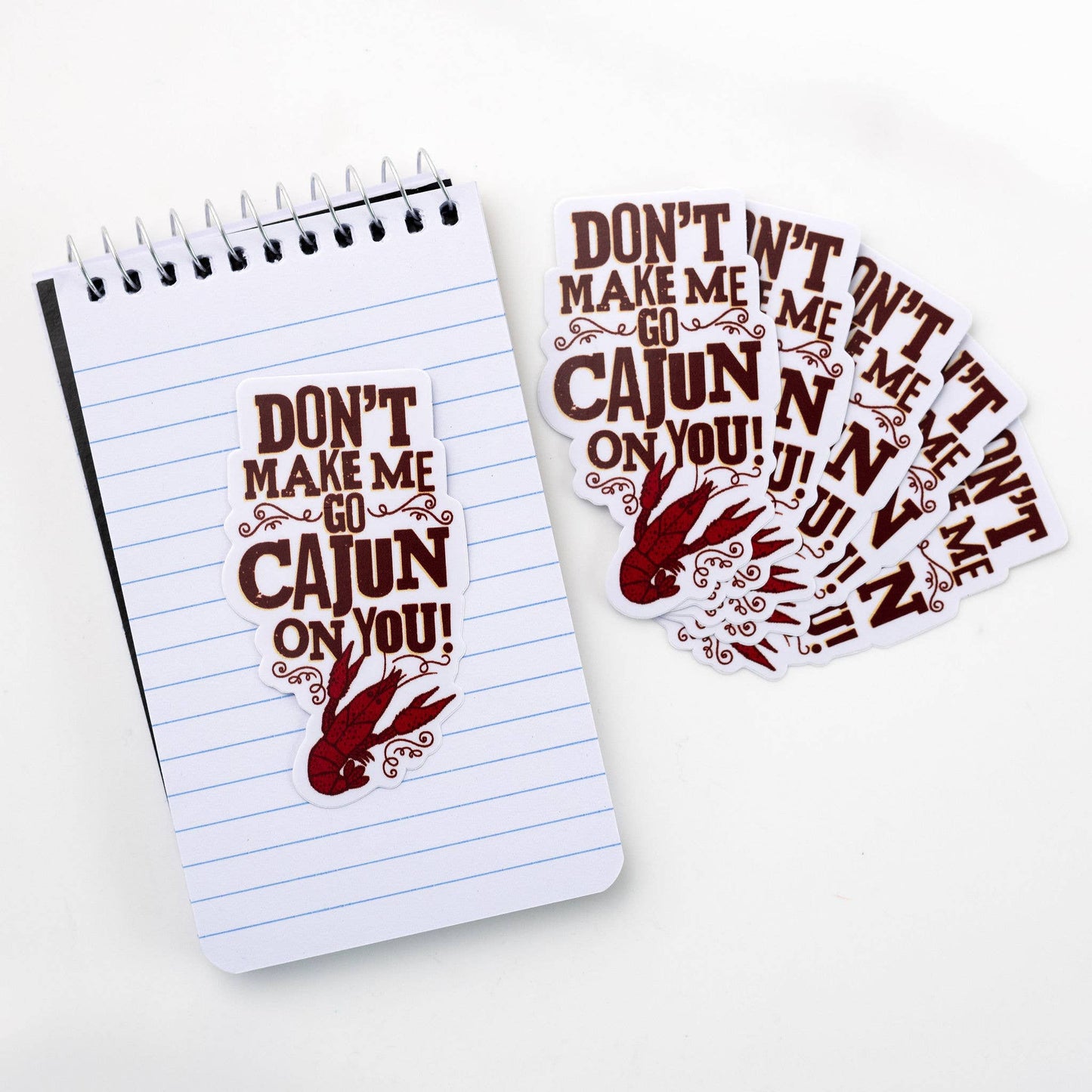 Notebook with 'Don't Make Me Go Cajun On You!' text and a set of matching stickers on a white background.