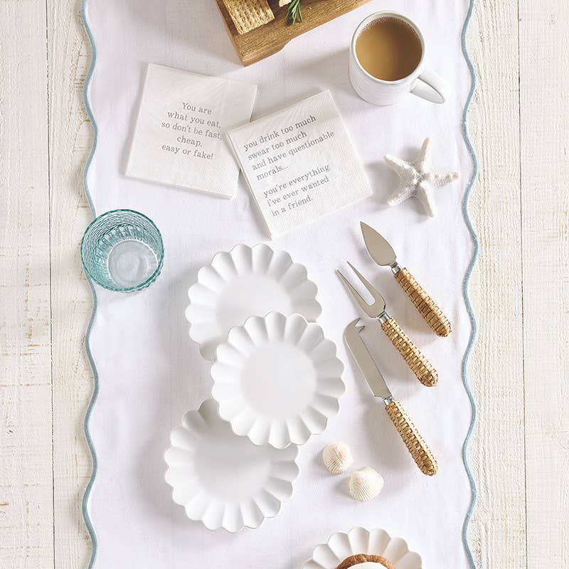 White ceramic plates with gold cutlery on a white surface with text cards and a cup.