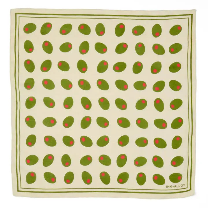 A square scarf featuring a repeating pattern of green olives with red pits on an off-white background, bordered by a green double-line frame. The brand name 'INK & ALLY' is printed in the bottom right corner.