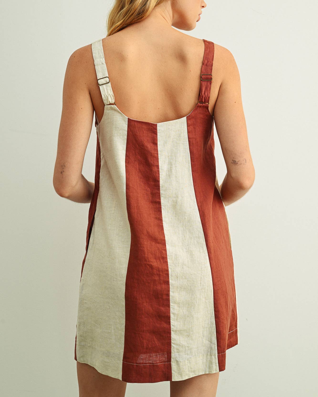 Woman wearing a red and white dress with thin straps on a plain background