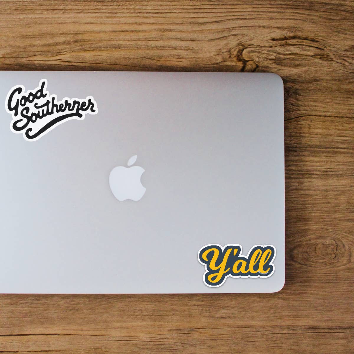 Silver laptop with 'Good Southerner' and 'Y'all' stickers on a wooden surface