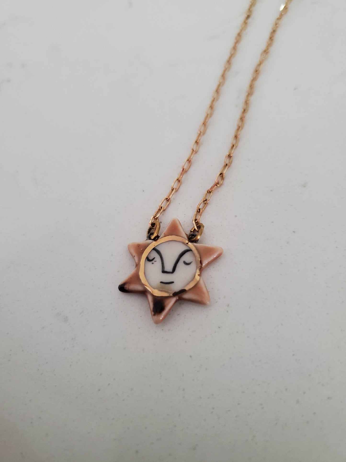 Star-shaped necklace with a face design on a light gray background