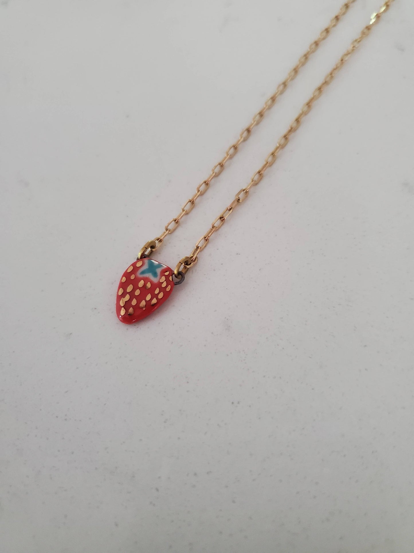 Necklace with a strawberry-shaped pendant on a light gray background