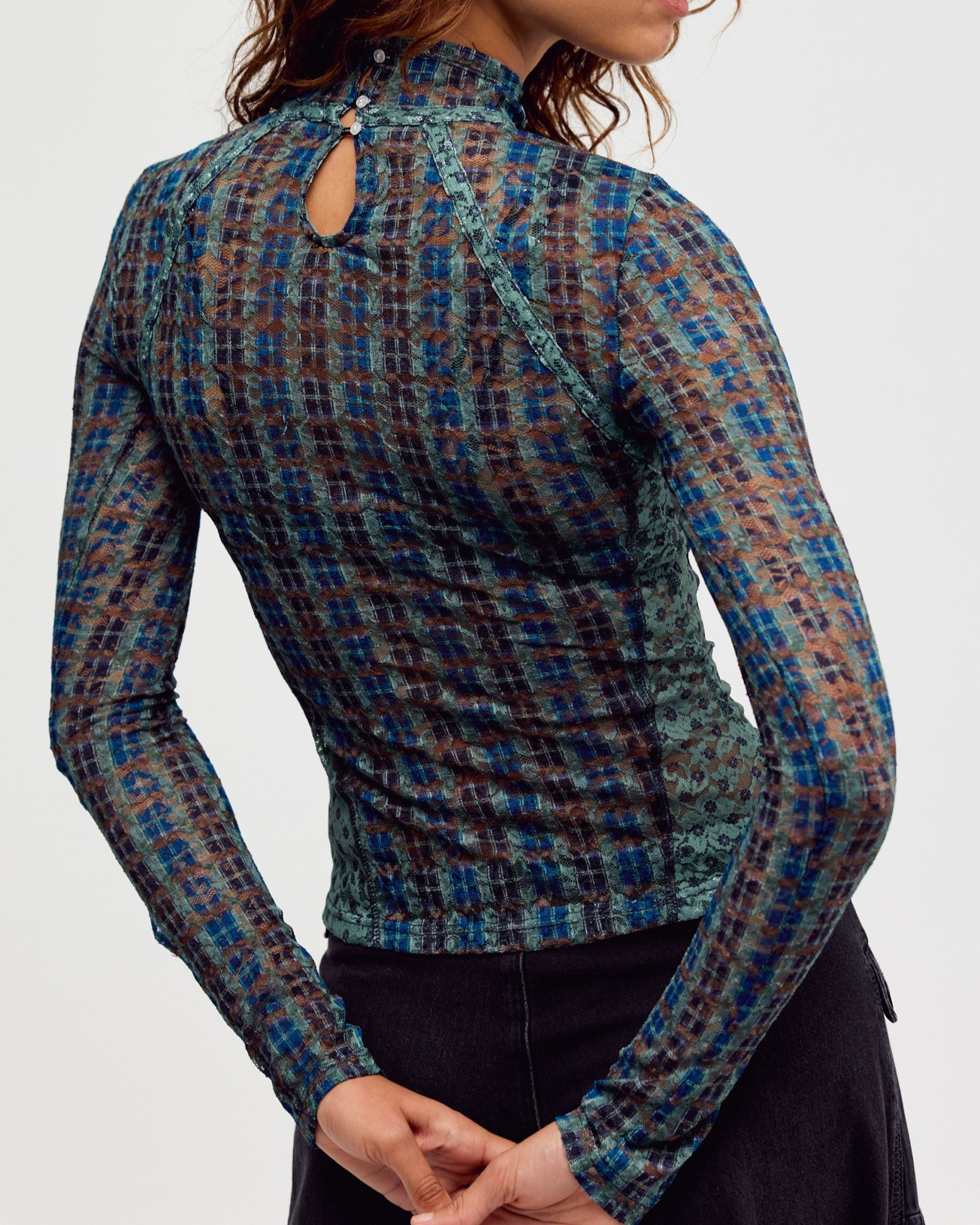 A woman shown from the back wearing a fitted long-sleeve top with a blue, brown, and black plaid pattern and a small keyhole cutout at the back neckline.