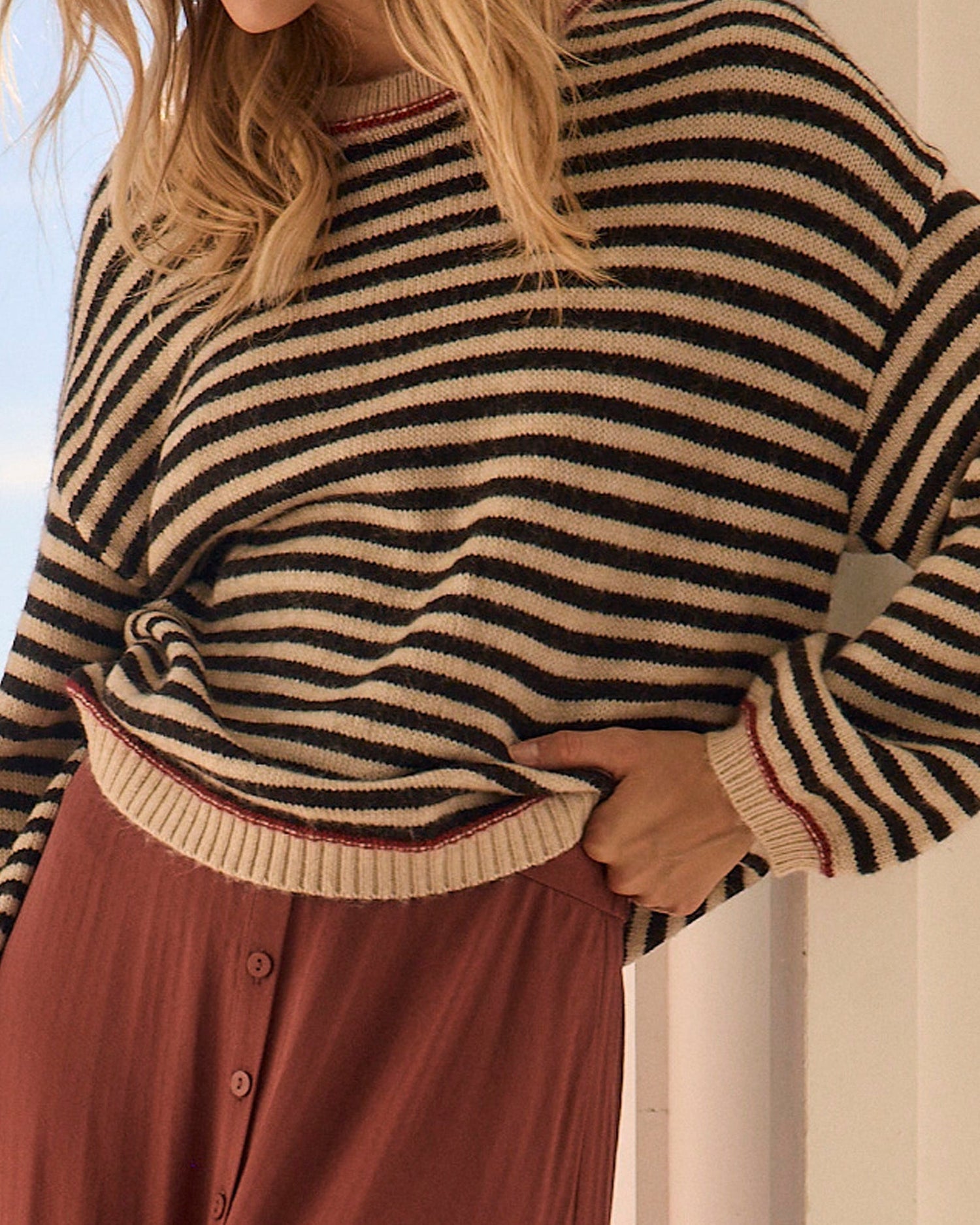 Woman wearing a red and white striped shirt with denim shorts against a neutral background