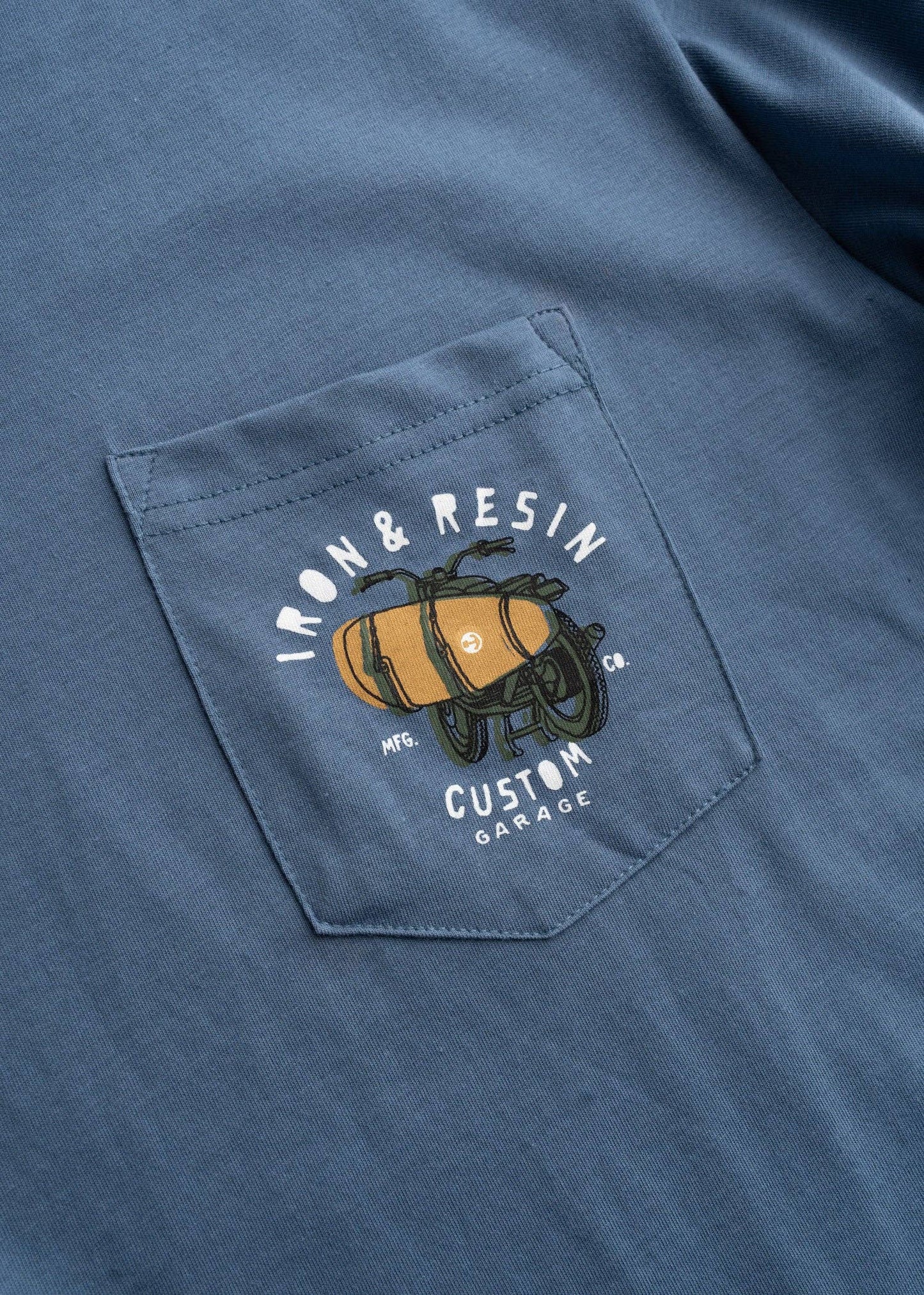 Blue shirt with a pocket featuring an embroidered design of a barrel and text.