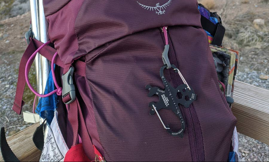 Maroon Osprey backpack with hiking gear in a desert setting, featuring a 'Great for Hikers' badge.