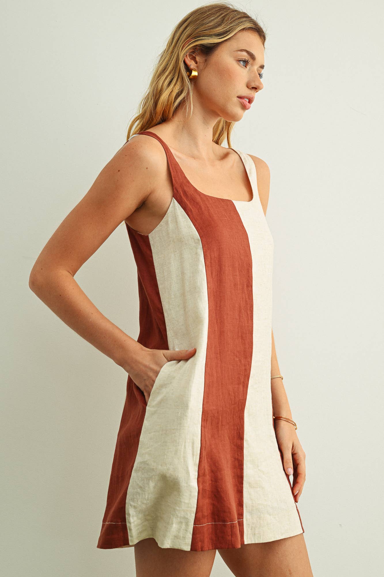 Woman wearing a sleeveless dress with a color-blocked design on a plain background