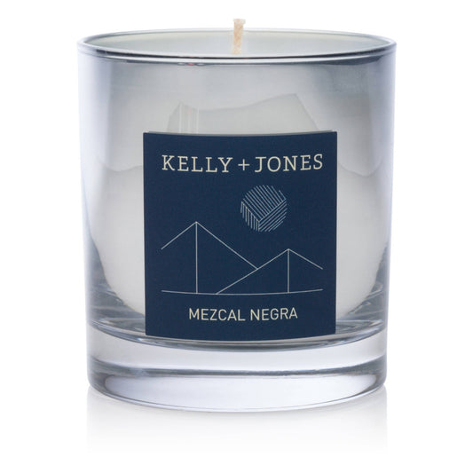 Clear glass candle with a navy label featuring 'Kelly + Jones' and 'Mezcal Negra' on a white background.